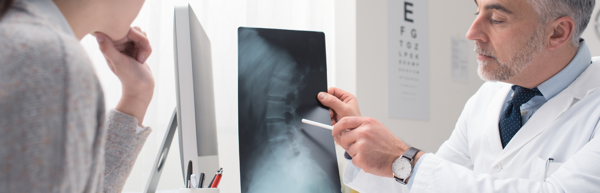 médico em seu consultório mostrando o resultado de um raio-x da coluna de uma paciente