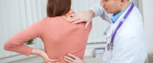 mulher com dor nas costas sendo examinada pelo médico